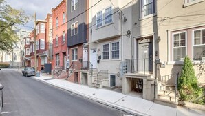 A row of townhouses with front stoops, a sidewalk, and a parked car. - Spacious 5-bedroom apartment in lovely Philadelphia with WiFi, Free Parking (Philadelphia)
