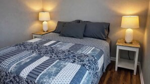 Ein Schlafzimmer mit einem Bett, zwei Nachttischen und zwei Lampen.