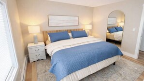 Une chambre à coucher avec un lit, des tables de chevet, un miroir et un tableau accroché au mur.