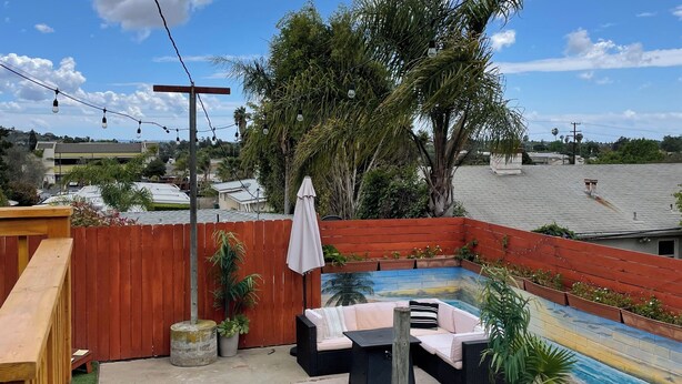 A backyard with a wooden deck, a small pool, outdoor furniture, and string lights. - Cozy 2Bed-Private Parking, Dog Friendly, Big Yard! (San Diego)