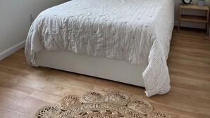 A bedroom with a bed, a ceiling fan, a window with blinds, a bedside table with a clock, and a woven rug. - Cozy 2Bed-Private Parking, Dog Friendly, Big Yard! (San Diego)