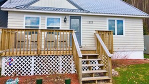 A single-story house with a front deck, a small porch, and a number '1323' on the side.