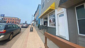 A street view with a building labeled 'Grand Island Fudge' and a sign for 'Muldoons Pasties.' - Upstairs Suite at the entrance to Pictured Rocks (Munising)