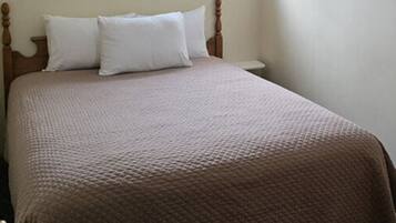 A bedroom with a bed, a window, an air conditioning unit, and a nightstand.