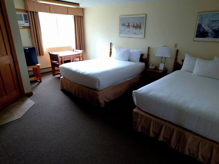 Ein Hotelzimmer mit zwei Betten, einem Schreibtisch, einem Sessel, einer Lampe und zwei Bildern an den Wänden.