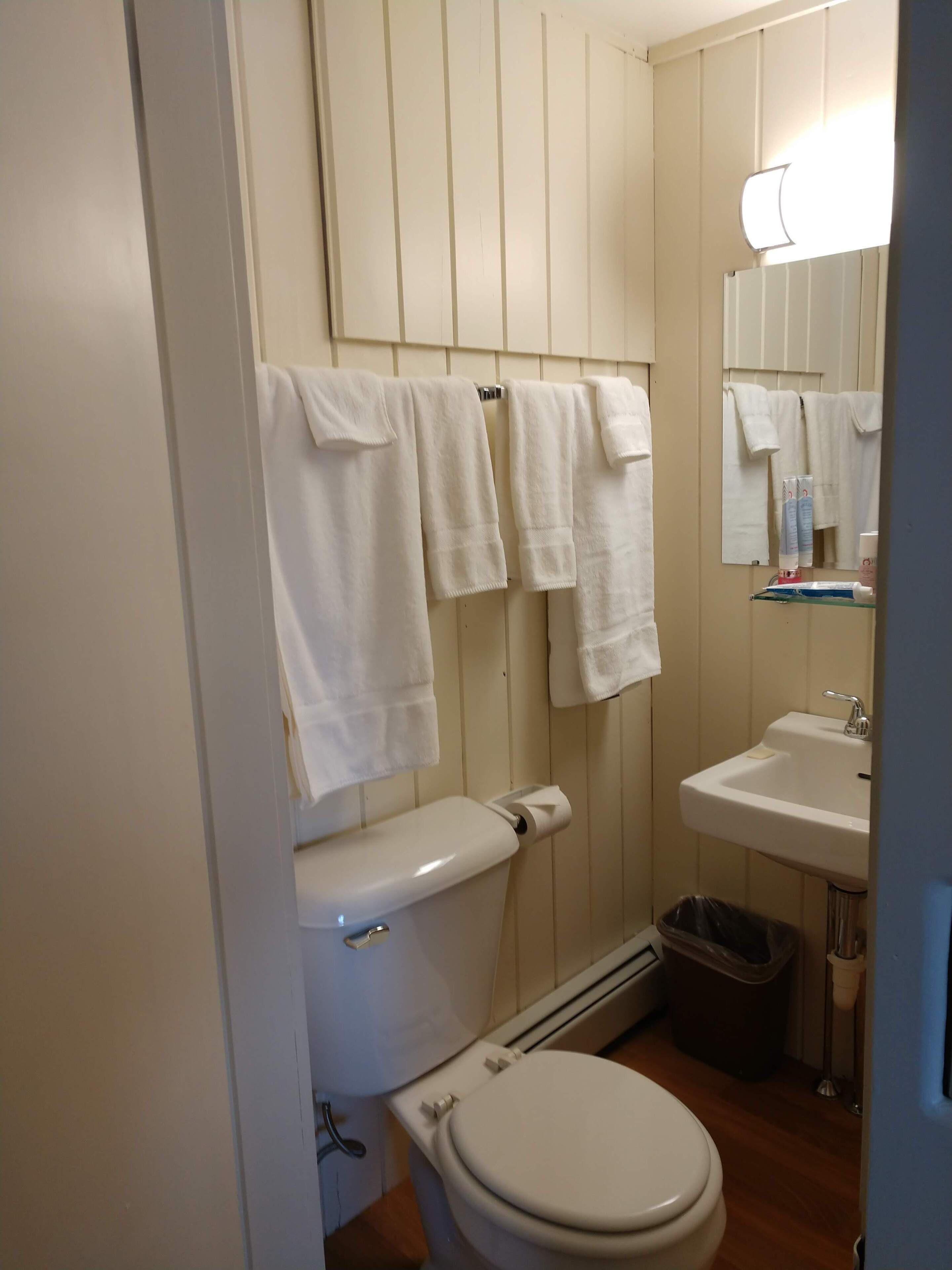 Un baño con inodoro, lavamanos y toallas colgadas.
