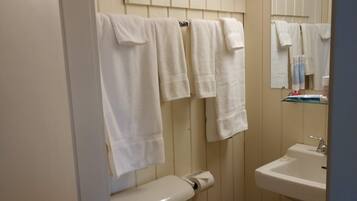 Un baño con inodoro, lavamanos y toallas colgadas.
