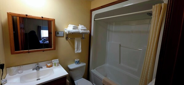 A bathroom with a sink, mirror, toilet, and shower. - Wilson Lake Inn (Wilton)