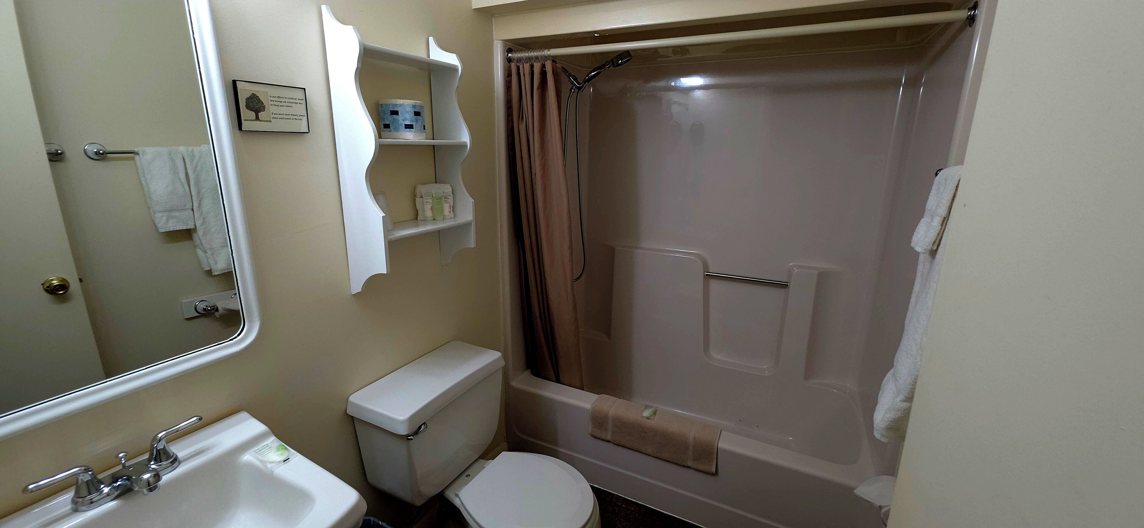 Un baño con inodoro, lavamanos, espejo, ducha y toallero.