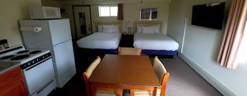 Habitación de hotel con kitchenette, dos camas, televisor y ventana.