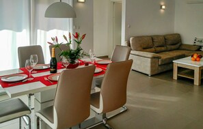 A dining area with a table set for two, a bottle of champagne, and a vase with flowers. - Lovely home in Vodnjan (Vodnjan)