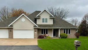 Une maison à deux étages avec un garage, une véranda et une pelouse bien entretenue.