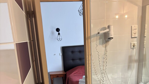 A hotel room with a bed, bedside table, and a bathroom with a sink and mirror. - Hotel beautiful stay in porto-ota 105 (Ota)