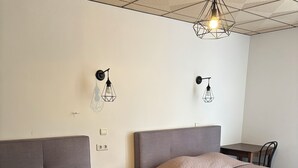 A hotel room with two beds, a wooden nightstand, a small table, and a hanging light fixture. - Hotel beautiful stay in porto-ota 105 (Ota)
