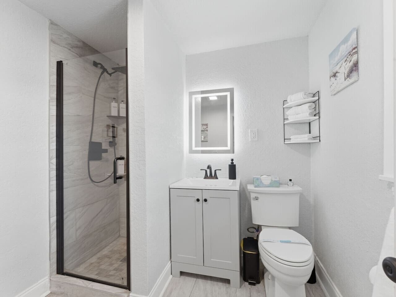 A modern bathroom with a glass shower enclosure, a white sink with a mirror, and a toilet.