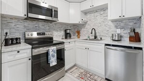A modern kitchen with white cabinets, a stainless steel microwave, a coffee maker, and a dishwasher. - Clearwater Top Floor #4 (Clearwater)