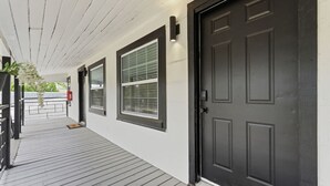 A covered porch with a black door, windows, and a fire alarm. - Clearwater Top Floor #4 (Clearwater)