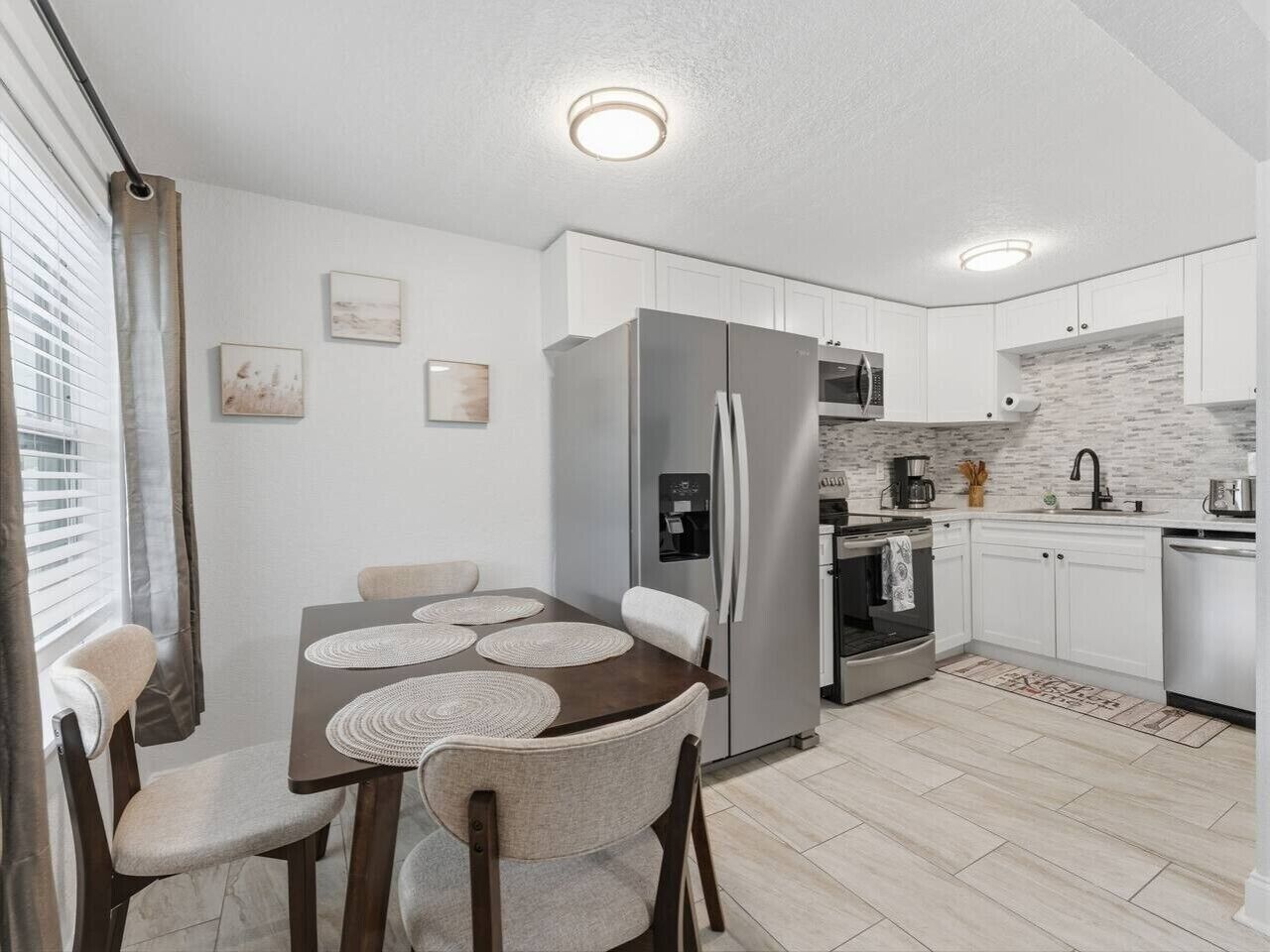A modern kitchen with white cabinets, a stainless steel refrigerator, a microwave, and a dishwasher.