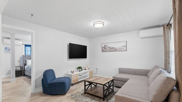 A modern living room with a sofa, armchair, TV, and a small table. - Clearwater Top Floor #4 (Clearwater)