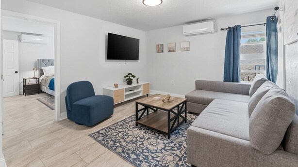 Una sala de estar moderna con un sofá, un sillón, una mesa de centro y un televisor de pantalla plana montado en la pared.