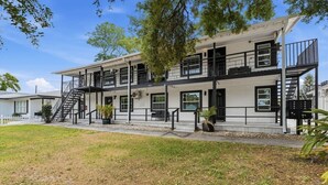 Un edificio de varios pisos con fachada blanca, barandales negros y una escalera que conduce a los pisos superiores.