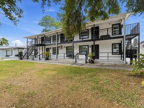A multi-story building with a white exterior, black railings, and a staircase leading to the upper floors. - Clearwater Top floor #5 (Clearwater)