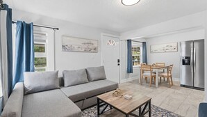 Una sala moderna con un sofá gris, una mesa de centro de madera y un comedor con mesa y sillas.