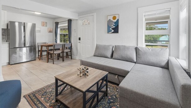 En moderne stue med en grå sofa, et træsofabord og et spiseområde med et bord og stole.