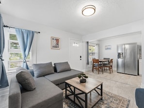 A modern living room with a sofa, coffee table, and dining area. - Clearwater First Floor #2 (Clearwater)