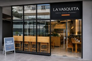 Ein Restaurant mit moderner Glasfassade, Holzsitzgelegenheiten und einem Schild, das Valet-Parking anzeigt.