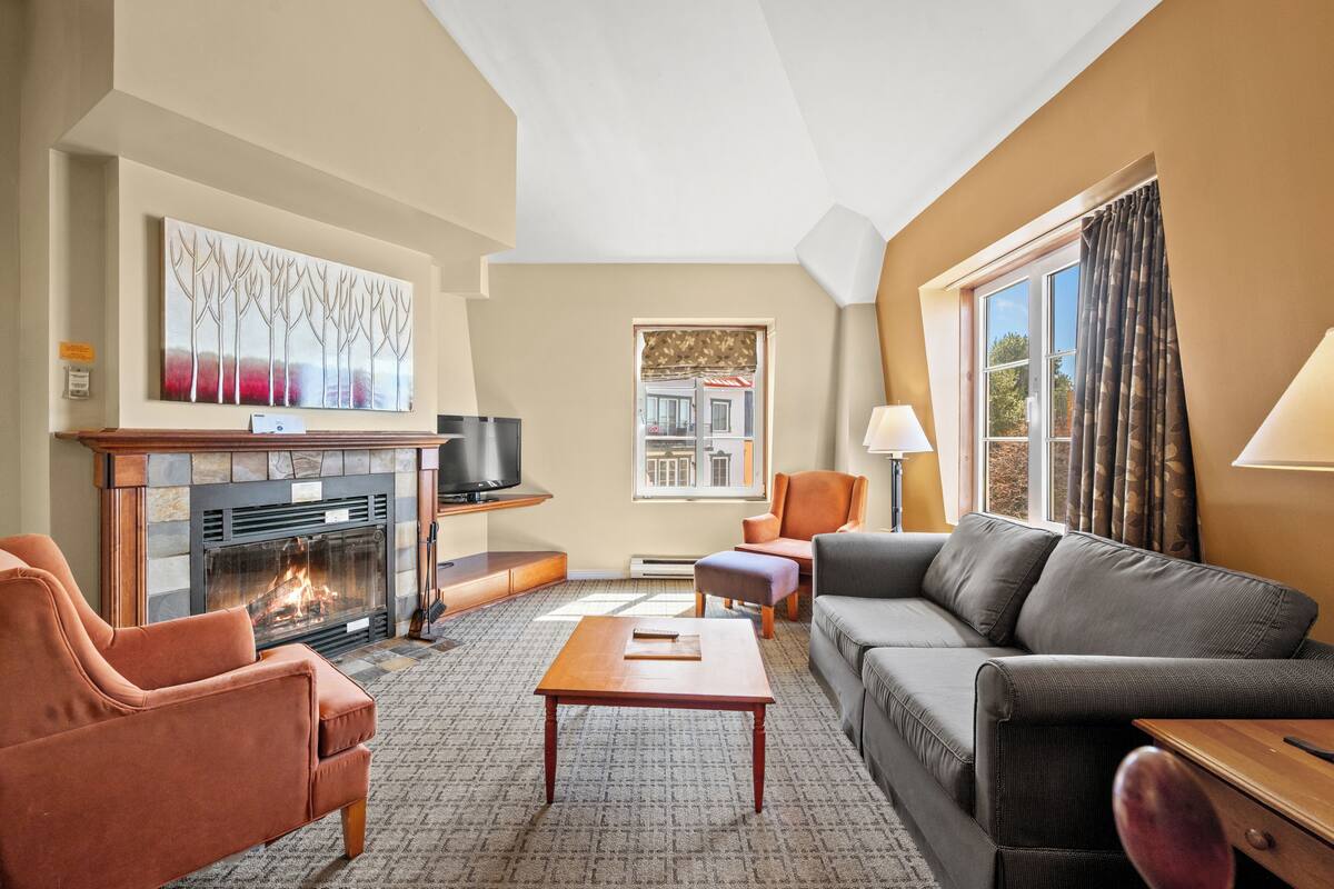 Una sala de estar con chimenea, sofá, sillón y televisor.
