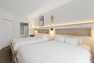 Habitación de hotel con dos camas, ducha, inodoro y un cuadro en la pared.