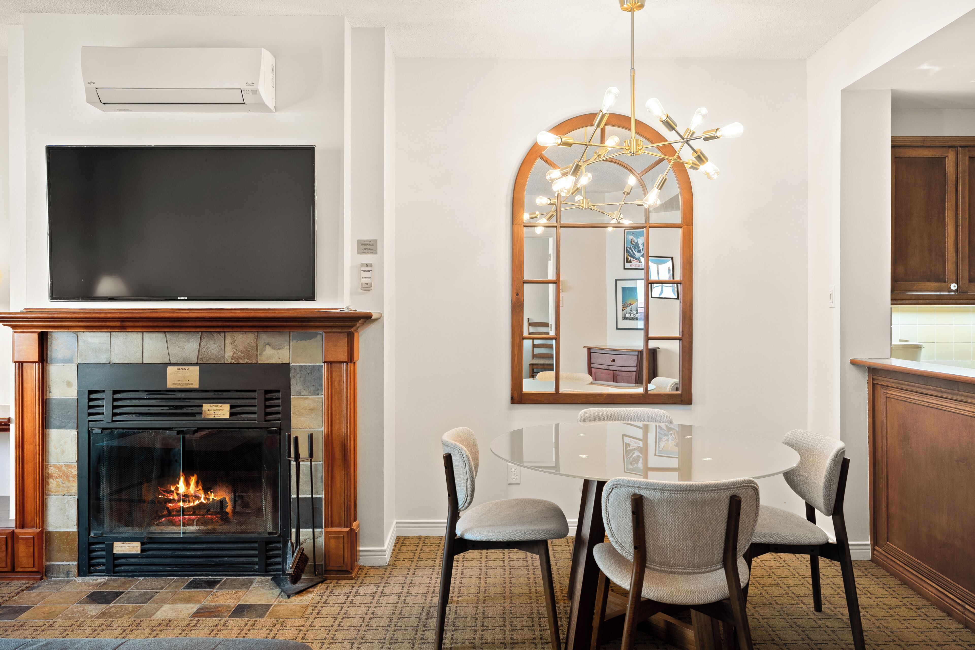 A dining area with a fireplace, a television, and a mirror.