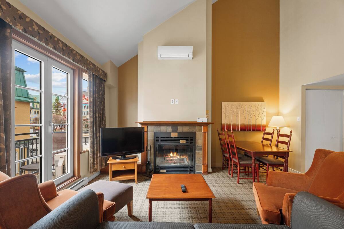 Una sala de estar con chimenea, televisor y zona de estar.