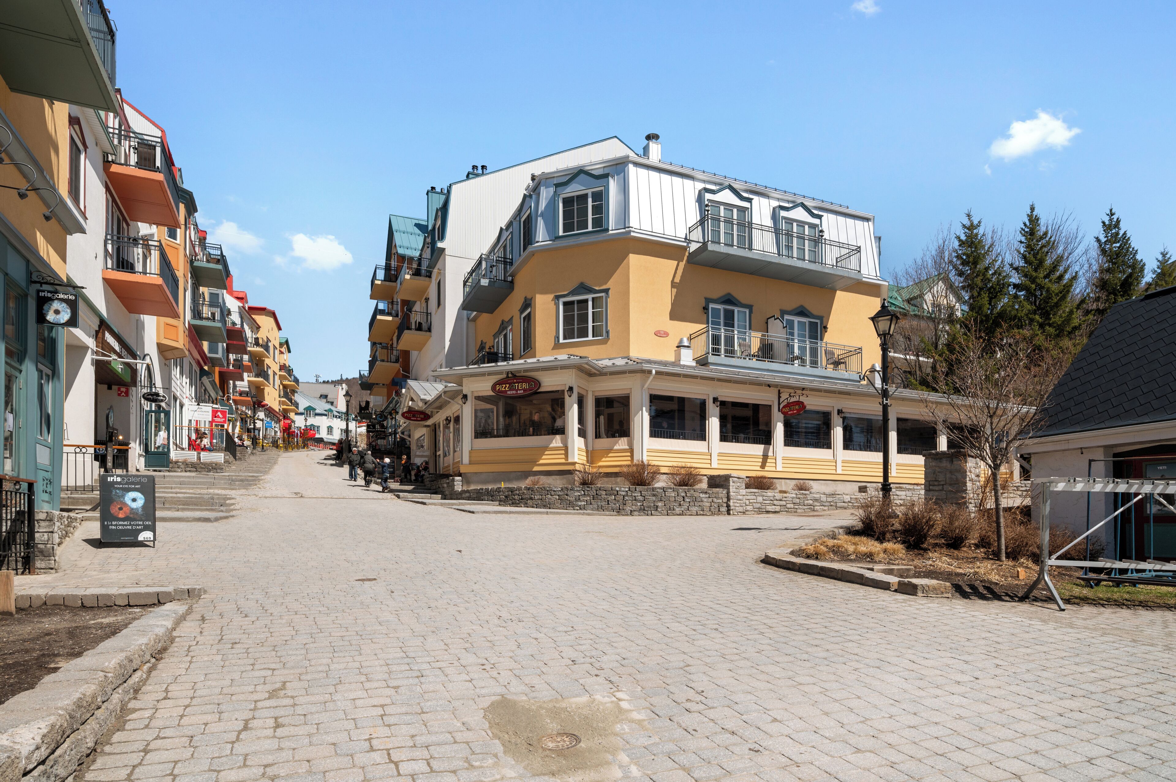 En gata med fler våningar, en restaurang som heter ”PIZZA TERIO” och en skylt för ”MUSICAL GALLERY”.