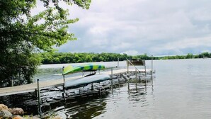Une jetée s’avançant dans un lac paisible, avec un parasol vert et bleu, entourée de rochers et d’arbres.