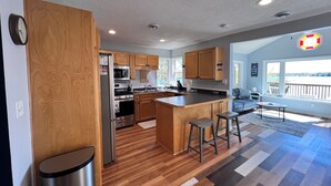 Une cuisine moderne avec des meubles en bois, des appareils électroménagers en acier inoxydable et un îlot central doté de tabourets.