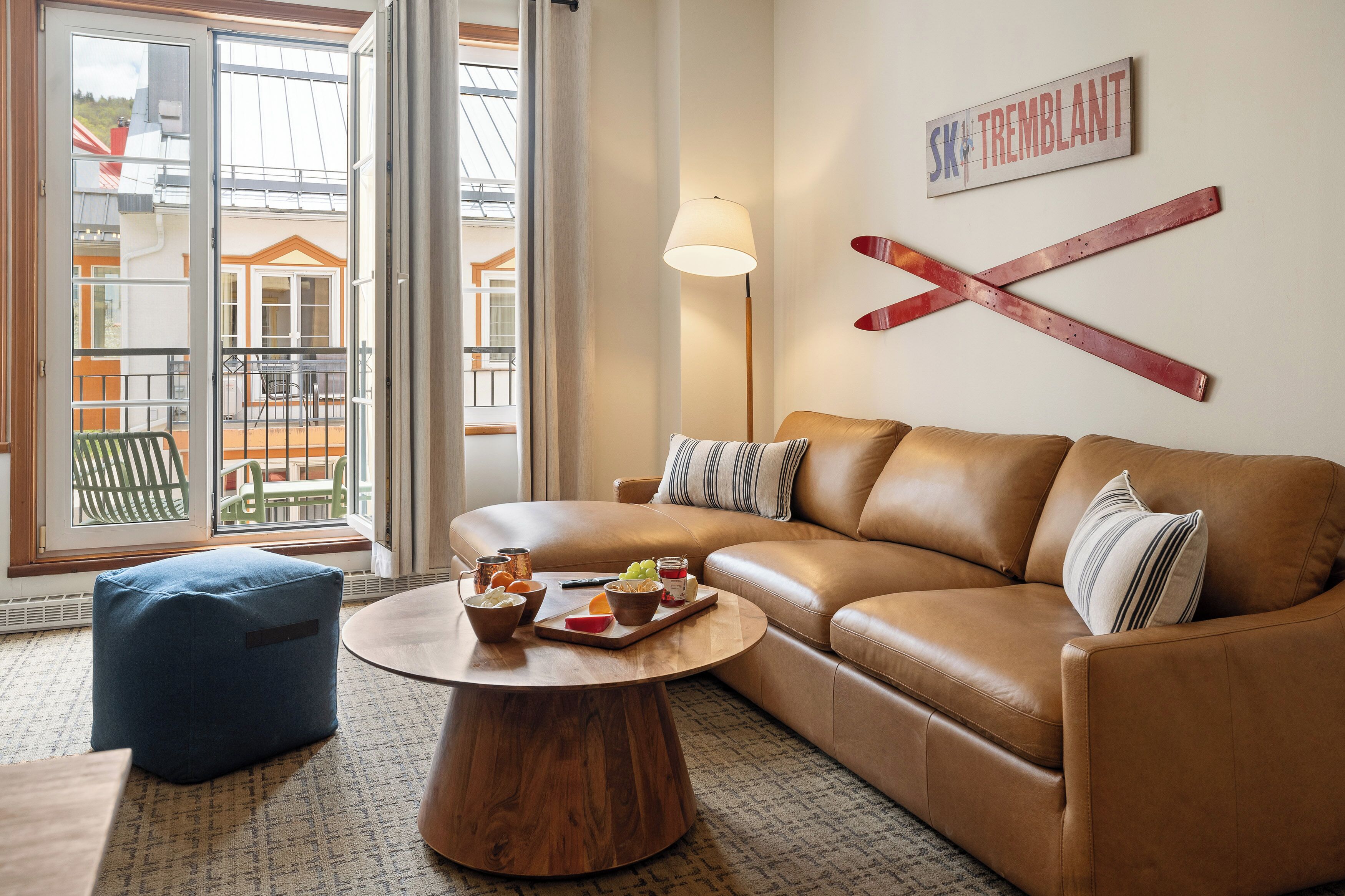 Ein Wohnzimmer mit Ledersofa, rundem Couchtisch und Blick auf einen Balkon.