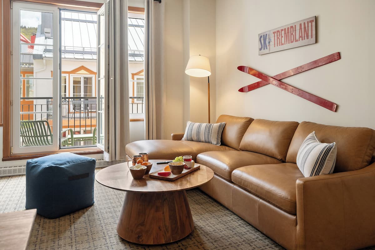 A living room with a leather sofa, a round coffee table, and a view of a balcony.