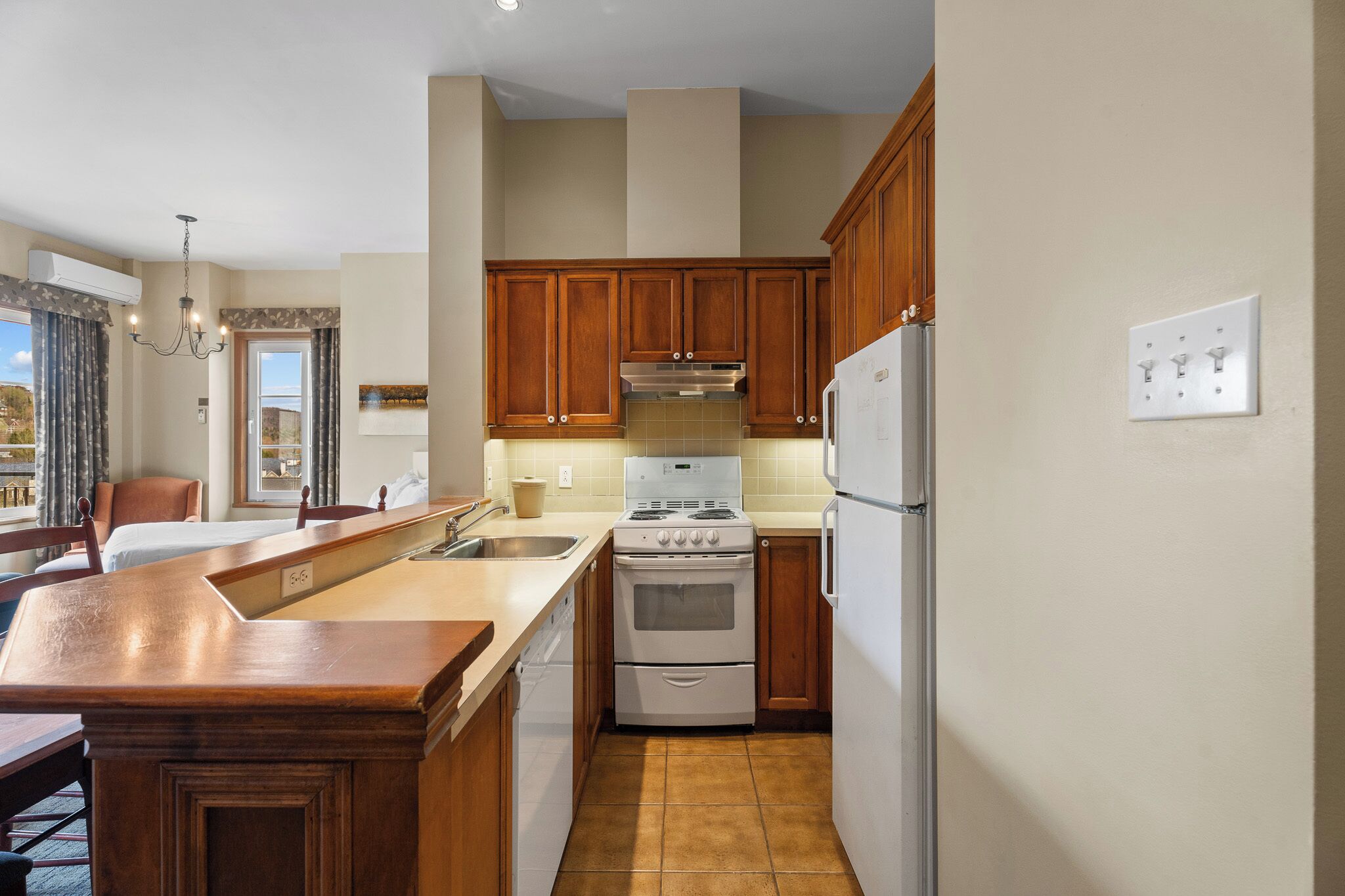 A compact kitchen with wooden cabinets, a built-in oven, and a refrigerator.
