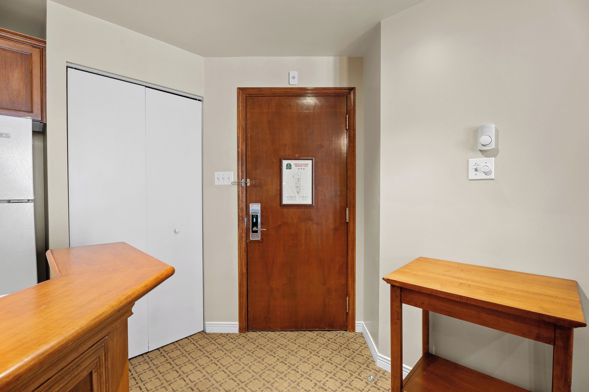 Un pasillo con una puerta de madera, una pared blanca y una pequeña mesa.