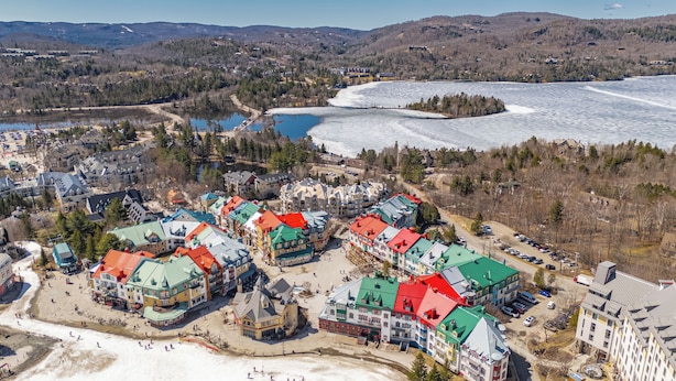 An aerial view of a resort area with buildings, a lake, and a snowy landscape. - Le Deslauriers by RVMT (Mont-Tremblant)