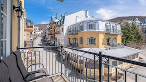 A hotel with a balcony, outdoor seating, and a view of the street. - Le Deslauriers by RVMT (Mont-Tremblant)