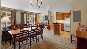 A spacious living room with a dining area, kitchen, and fireplace. - Le Deslauriers by RVMT (Mont-Tremblant)