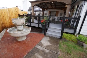 Un patio con una fuente de piedra, mobiliario exterior y una valla de madera.