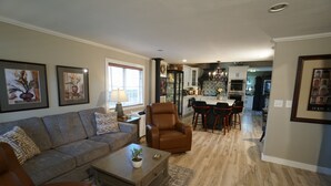 Un salon comprenant un canapé, un fauteuil, une table basse et un coin repas avec des chaises et une table.