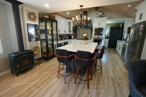 A kitchen with a central island, bar stools, a chandelier, and a wood-burning stove. - Modern European getaway. . WORLD CUP 2026 train (Puyallup)