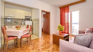 Un espacio habitable compacto con cocina, comedor y un balcón con cortinas rojas.