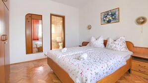 Un dormitorio con una cama de madera, un espejo, un cuadro y una mesita de noche.
