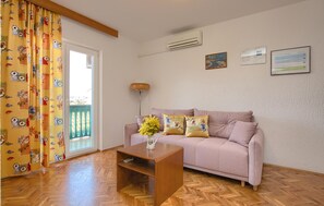 A living room with a sofa, a coffee table, a vase with flowers, a lamp, and a window with curtains. - Cozy apartment in Pula with WiFi (Pula)
